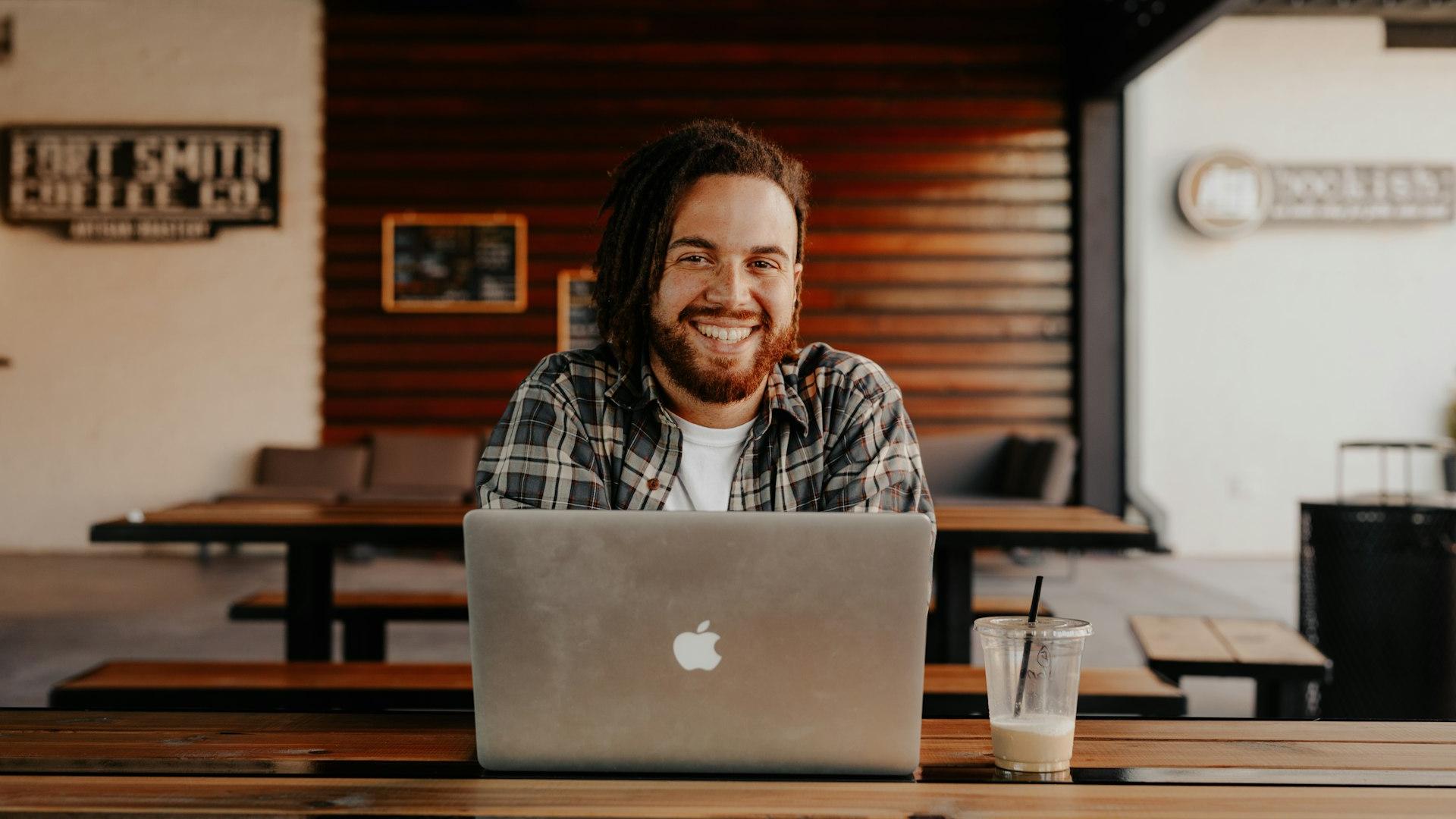 man in black and white striped polo shirt sitting on chair in front of silver macbook